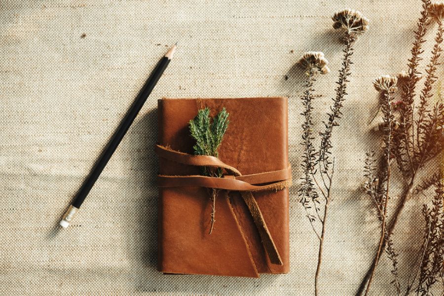 Harnessing the Power of Journaling for Personal Growth: A Comprehensive Guide 4 closed leather bound journal on a table with lavender flower and pen. Flay lay image.