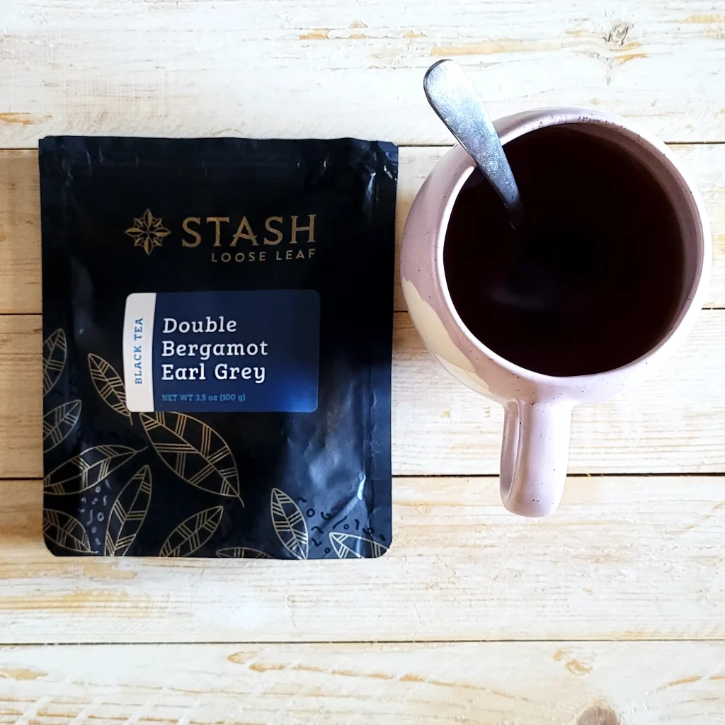 Best Earl Grey Tea: 9 Top Contenders Compared in 2024 10 a pink cup filled with earl greay double stash tea and the loose tea bag on a coffee table ready for tasting.