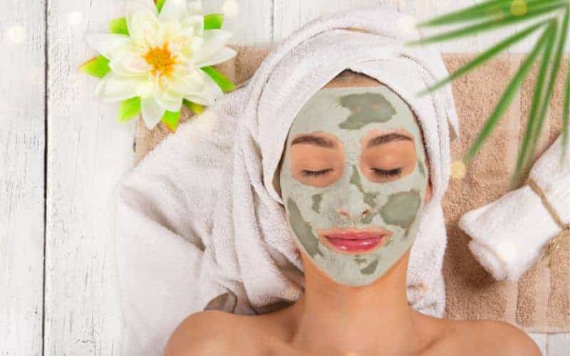 woman laid on her back with mud mask on