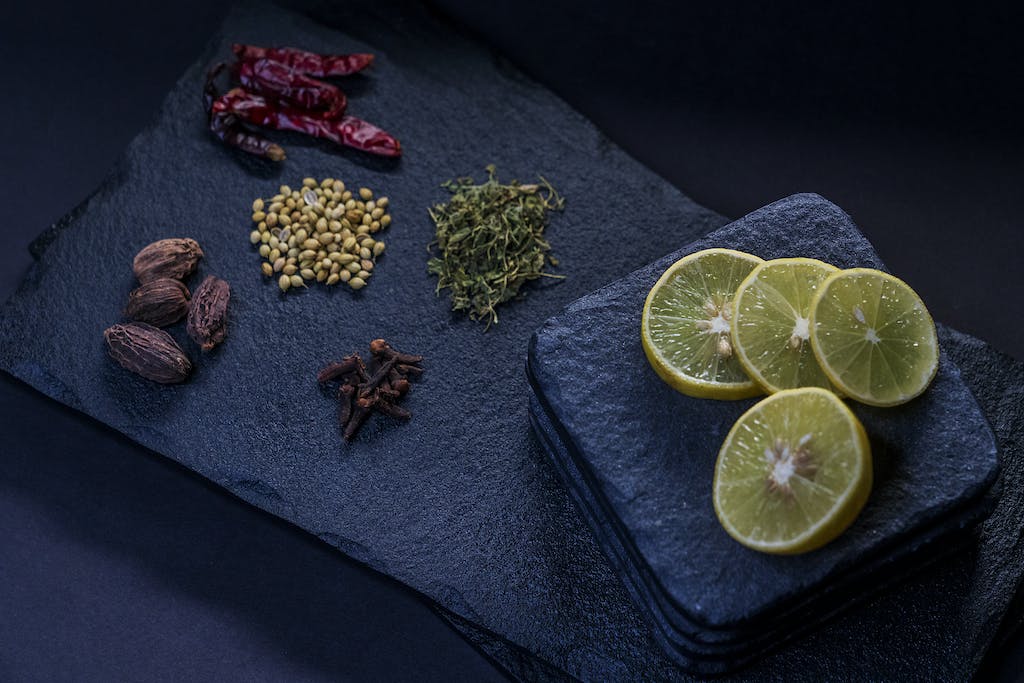 Non Toxic Cutting Boards: Top Picks for a Healthy Kitchen in 2024 5 From above of dried chili peppers near thyme and pine nuts with cloves and ripe lemon slices on stone cutting board
